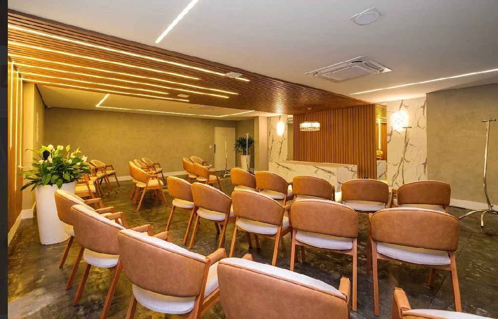Vista posterior da sala cerimonial com poltronas e painel de madeira